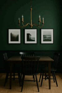 Forest-green dining room with black picture frames and brass chandelier.
